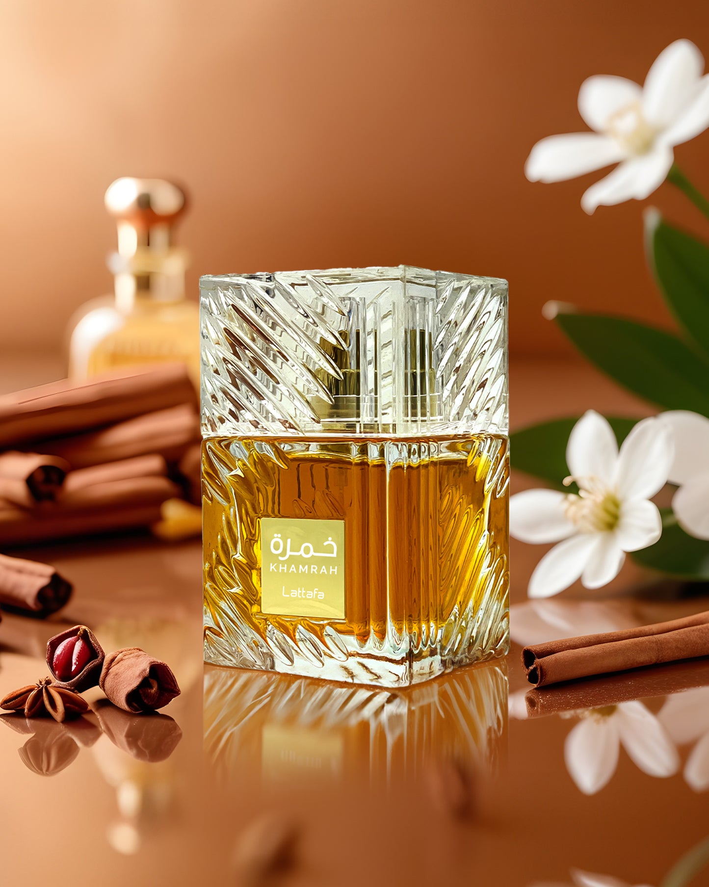 KHAMRAH EAU DE PARFUM perfume bottle photograph over reflected surface and surrounded with cinnamon and white flowers