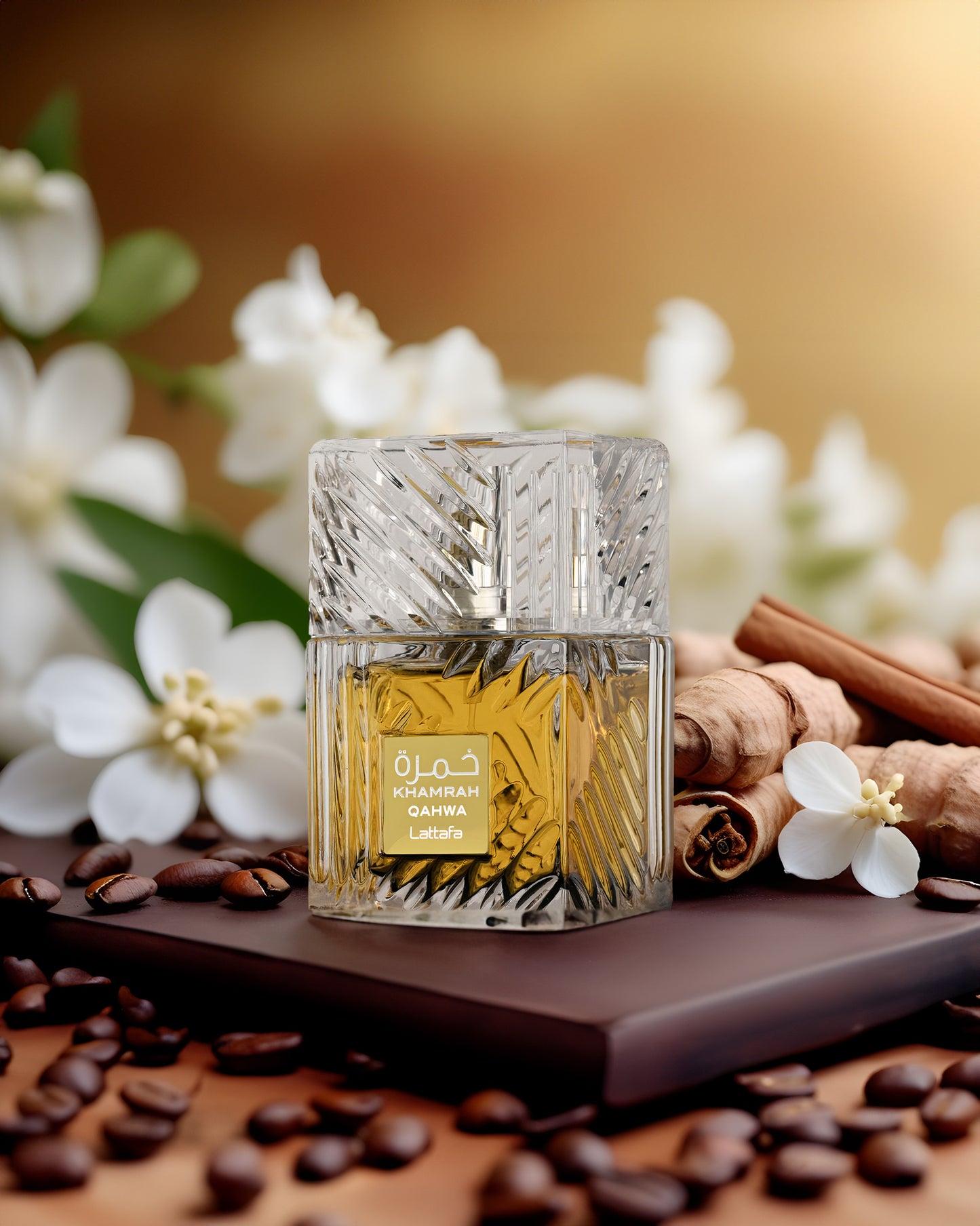 Khamrah Qahwa edp perfume bottle photograph beside cinnamon with background white flowers.