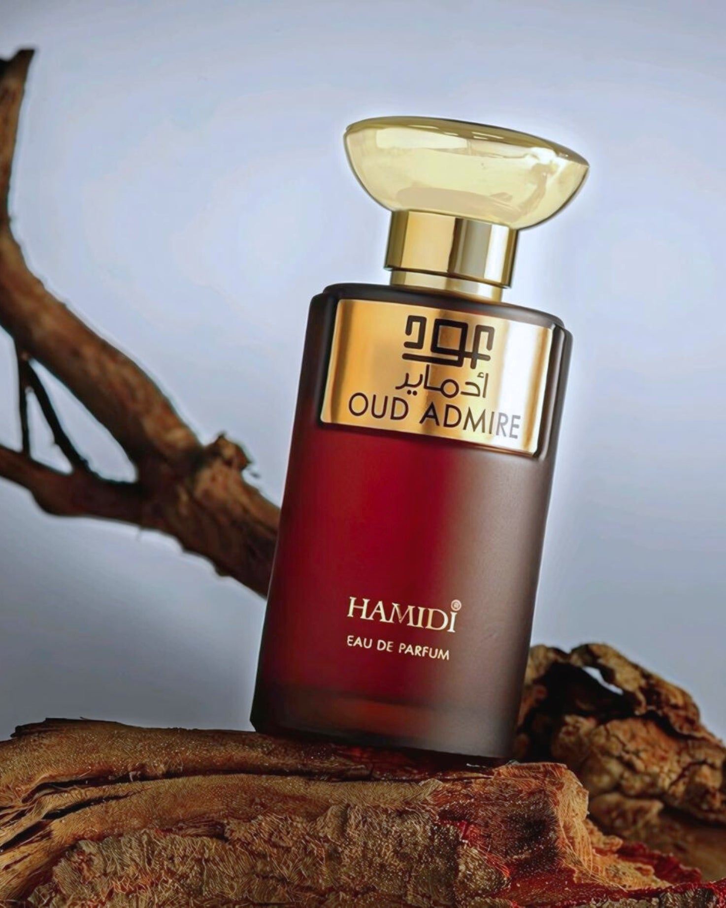 OUD Admire perfume bottle photograph over a woodlog against sunset