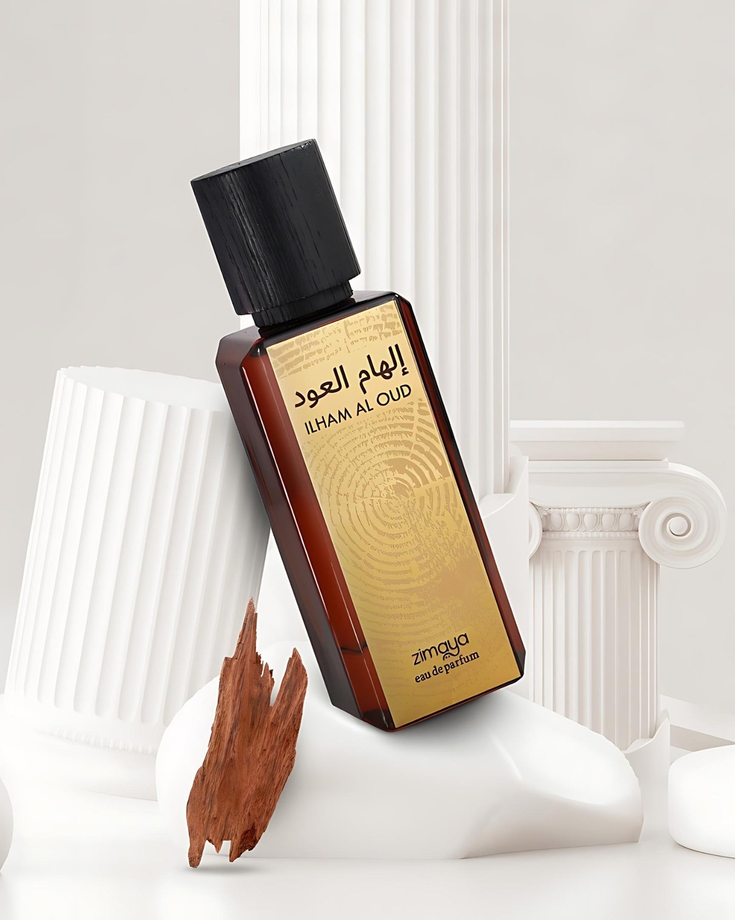 ilham al oud perfume bottle photograph against white marble beside oud wood