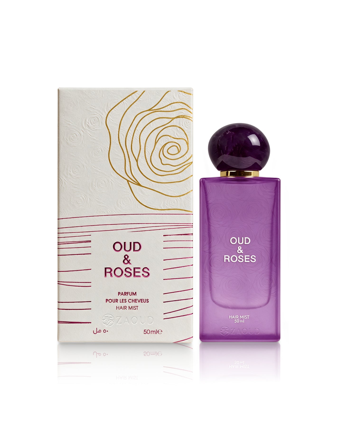 Oud & Roses hair mist 50ml bottle in purple glass next to its white and gold packaging box, on a clean white background with a soft reflection.