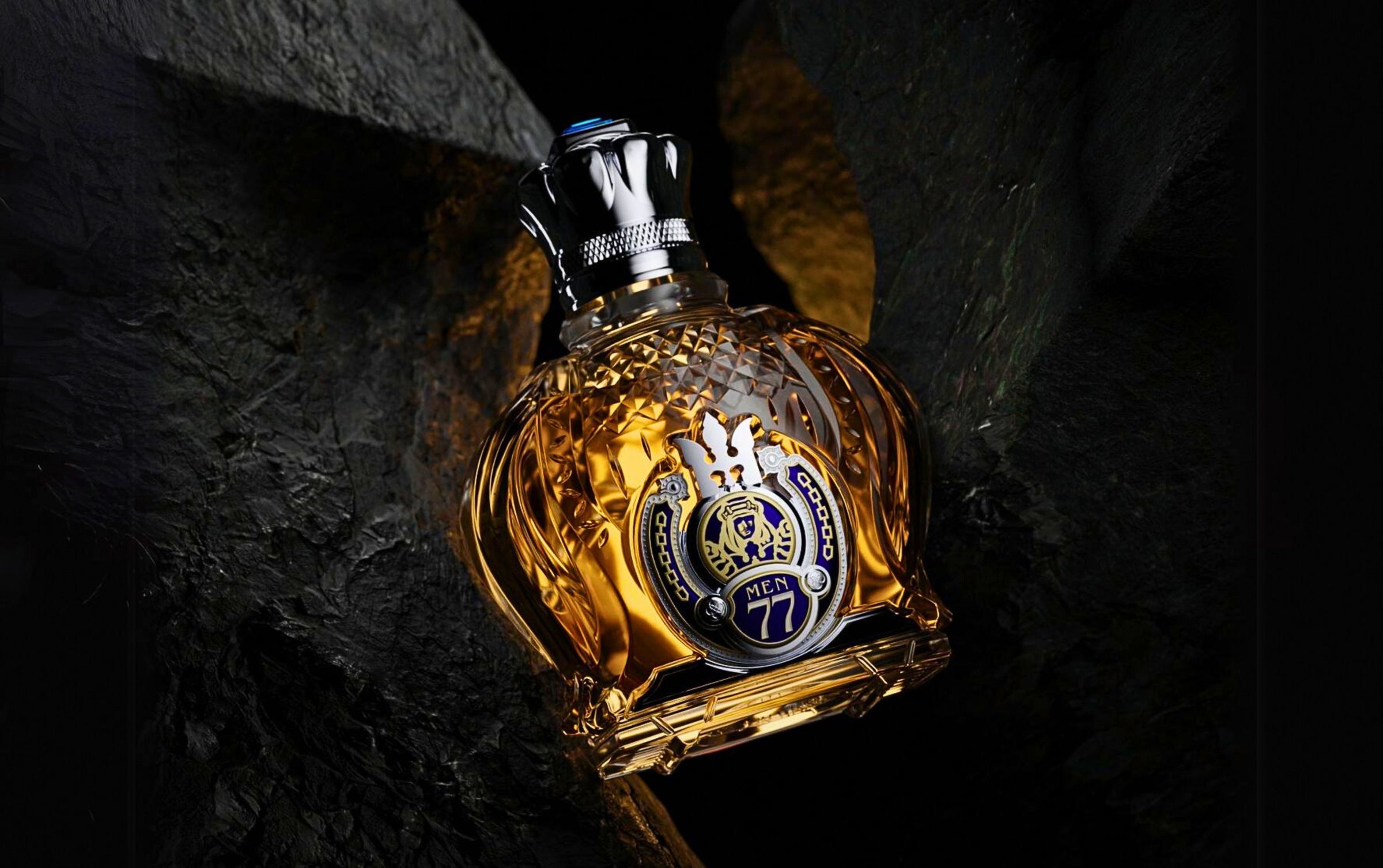 designer shaik gold men perfume bottle between dark rock crack