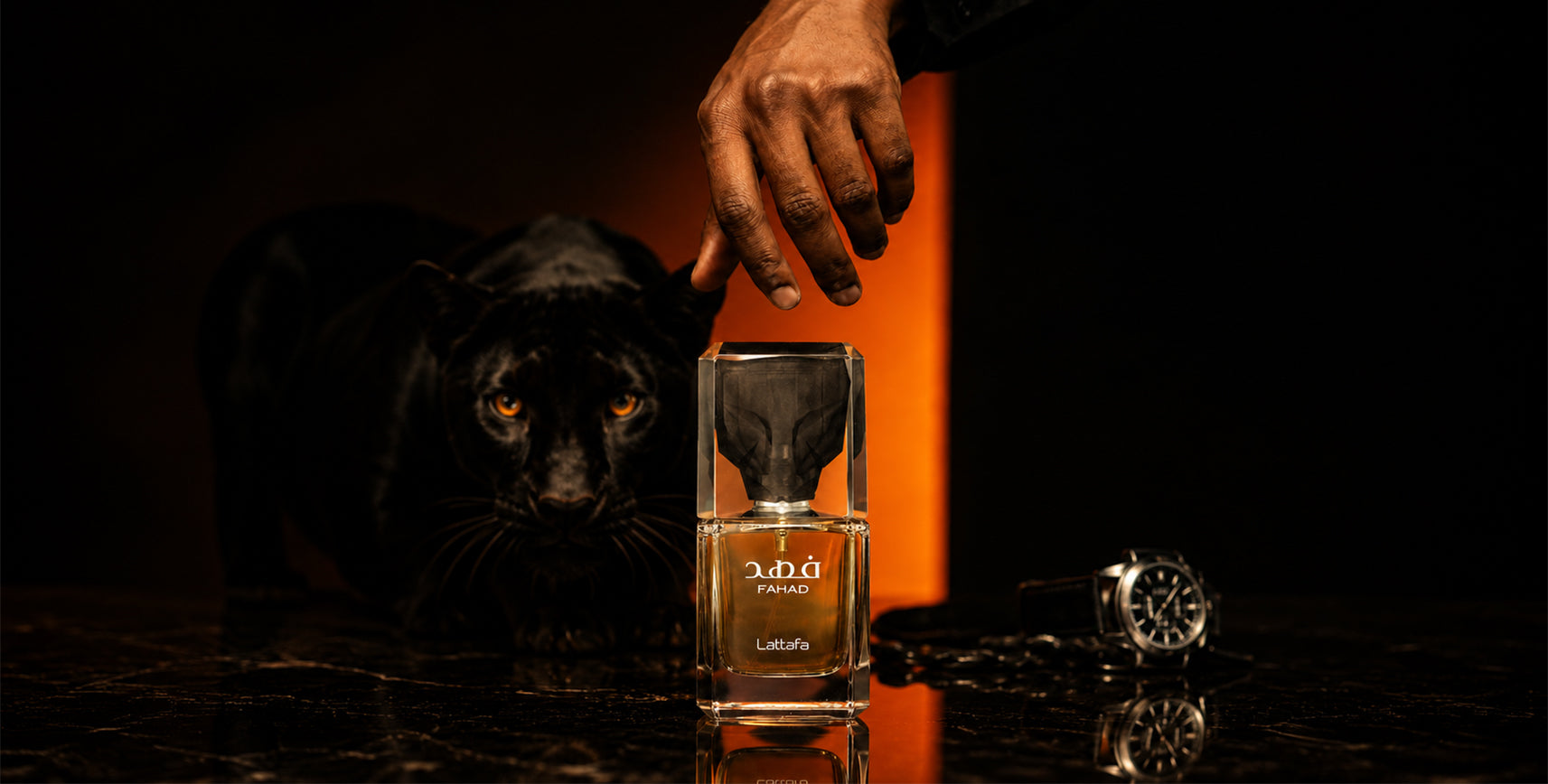 A clear rectangular perfume bottle labeled Fahad by Lattafa stands on a dark reflective surface, with a black panther behind it and a human hand reaching toward the bottle. A silver watch lies to the right against a dramatic orange-lit black background.