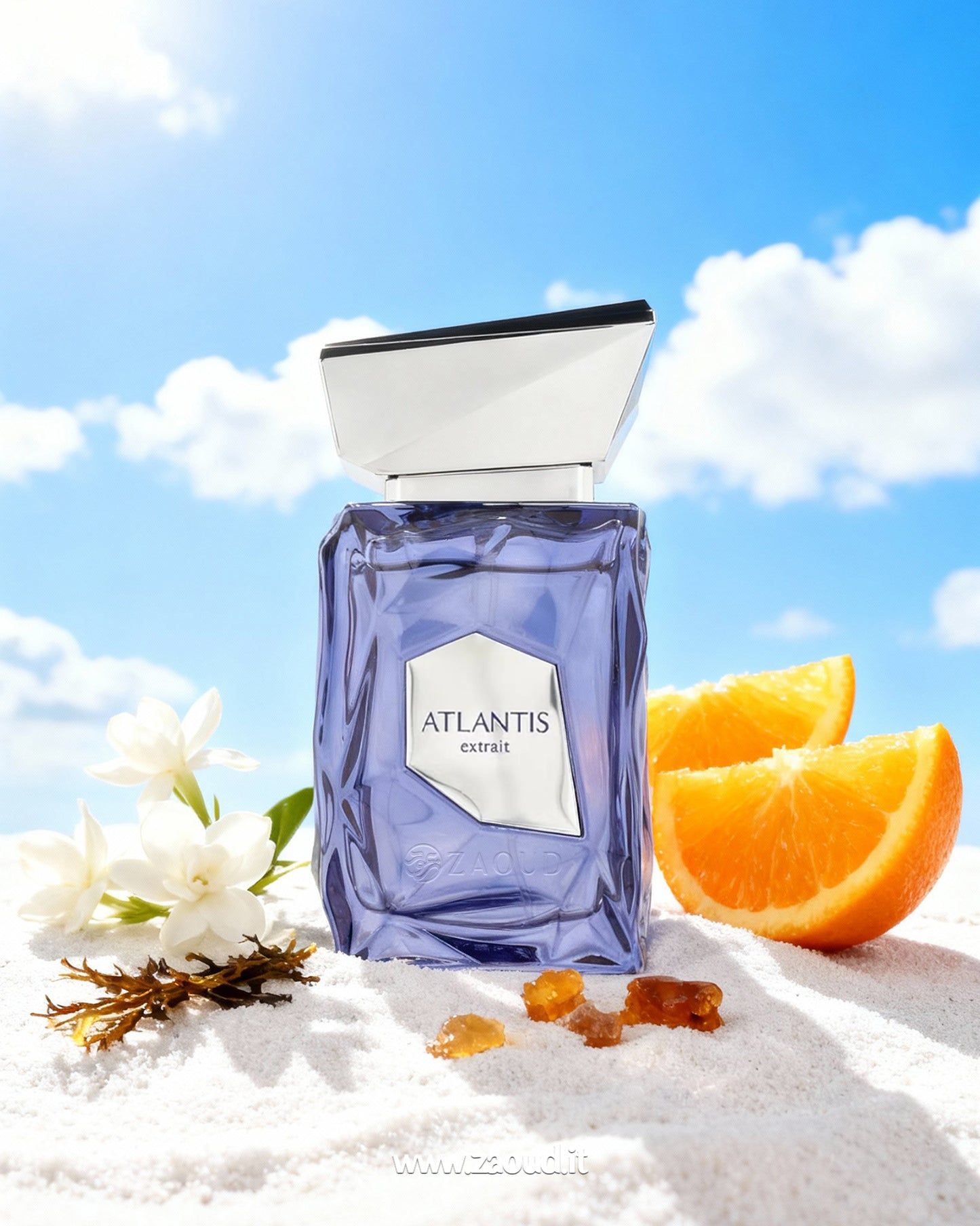 Perfume bottle labeled 'Atlantis' with orange slices and flowers on a sandy surface with a blue sky.