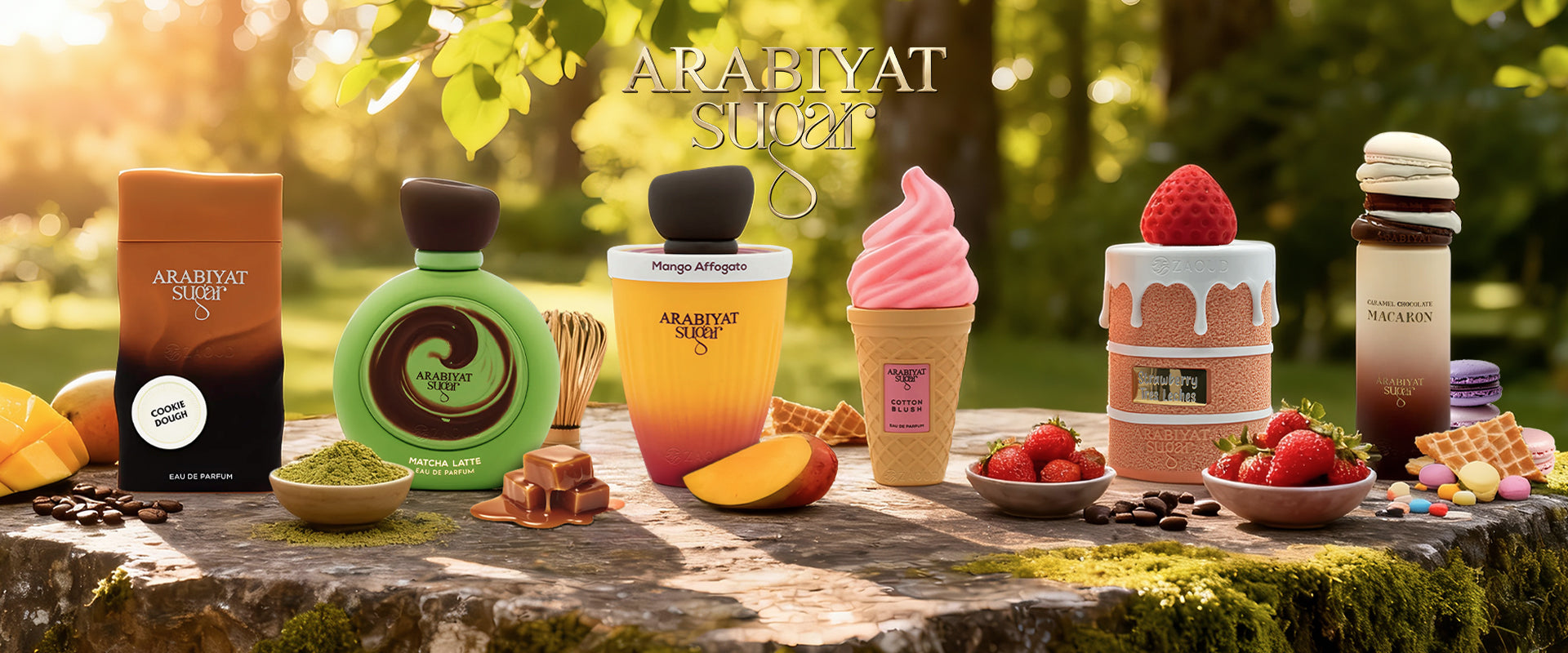 Arabiyat Sugar perfume collection featuring six dessert-themed bottles Cookie Dough, Matcha Latte, Mango Affogato, Cotton Blush, Strawberry Tres Leches, and Macaron displayed on a rustic stone slab surrounded by fresh ingredients like mangoes, strawberries, and matcha powder in a sunlit garden