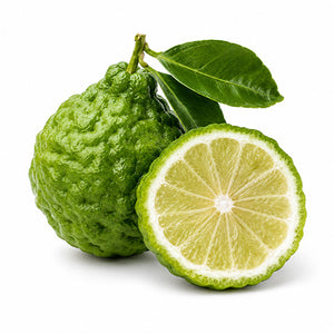 A green bergamot with two dark green leaves, shown next to a cross-section of the same fruit revealing its segmented yellow-green pulp, isolated on a white background.