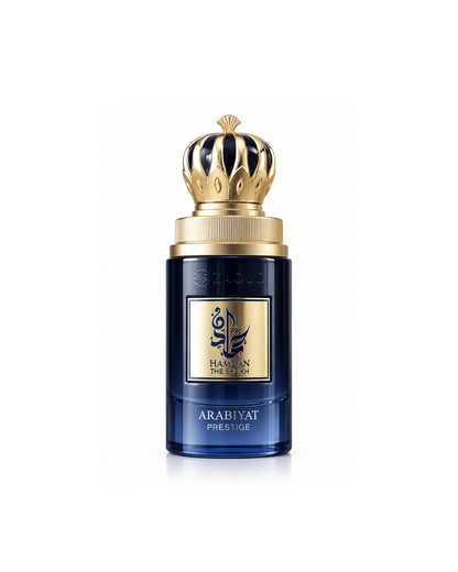 A bottle of Arabiyat prestige hamdan the sheikh, featuring a deep blue glass body with a prominent gold crown cap and a gold label on the front.