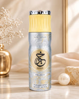 A bottle of Khair Paris Corner Felicity Perfumed Spray, 200 ml, standing on a marble surface with a gold vase and dried flowers on the left, and a pearl and textured stone on the right, against a warm beige background.