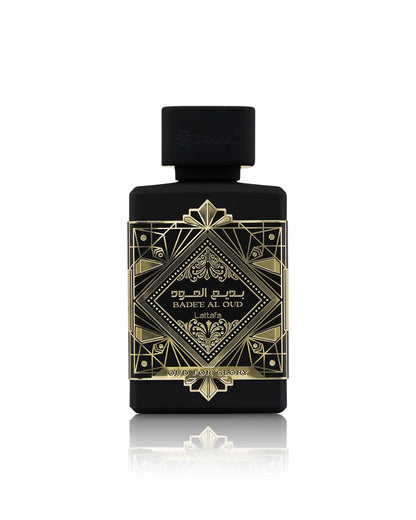 lattafa badee al oud oud for glory perfume bottle with a black cap, featuring an ornate gold geometric label with Arabic and English text, set against a clean white background with a soft reflection below.