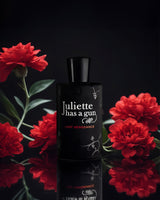 Lady Vengeance edp perfume bottle photograph besides red flowers