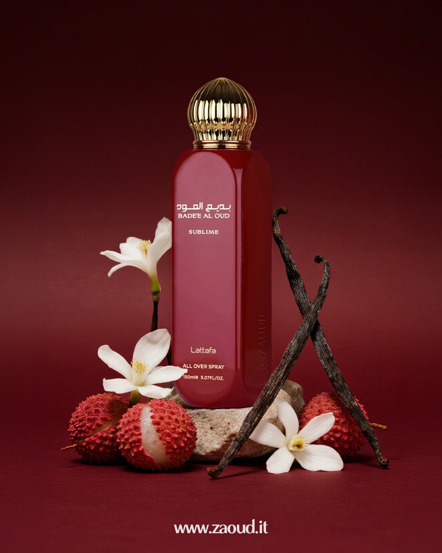 Badee Al Oud Sublime by Lattafa, placed with white flowers, lychee fruits, vanilla beans, and a stone, against a dark red background.