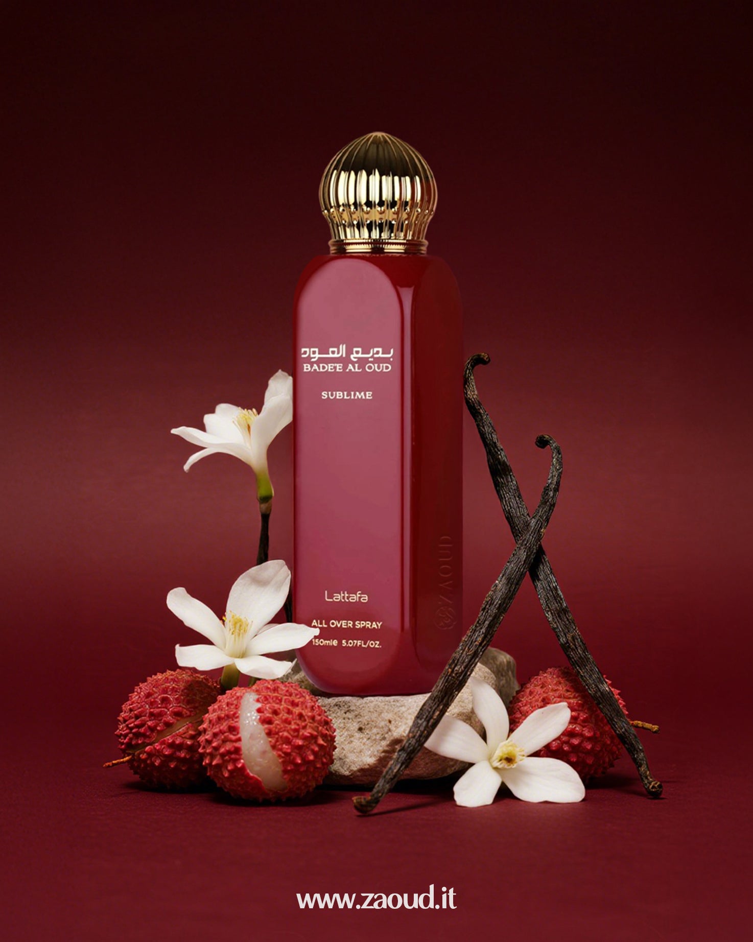 Badee Al Oud Sublime by Lattafa, placed with white flowers, lychee fruits, vanilla beans, and a stone, against a dark red background.