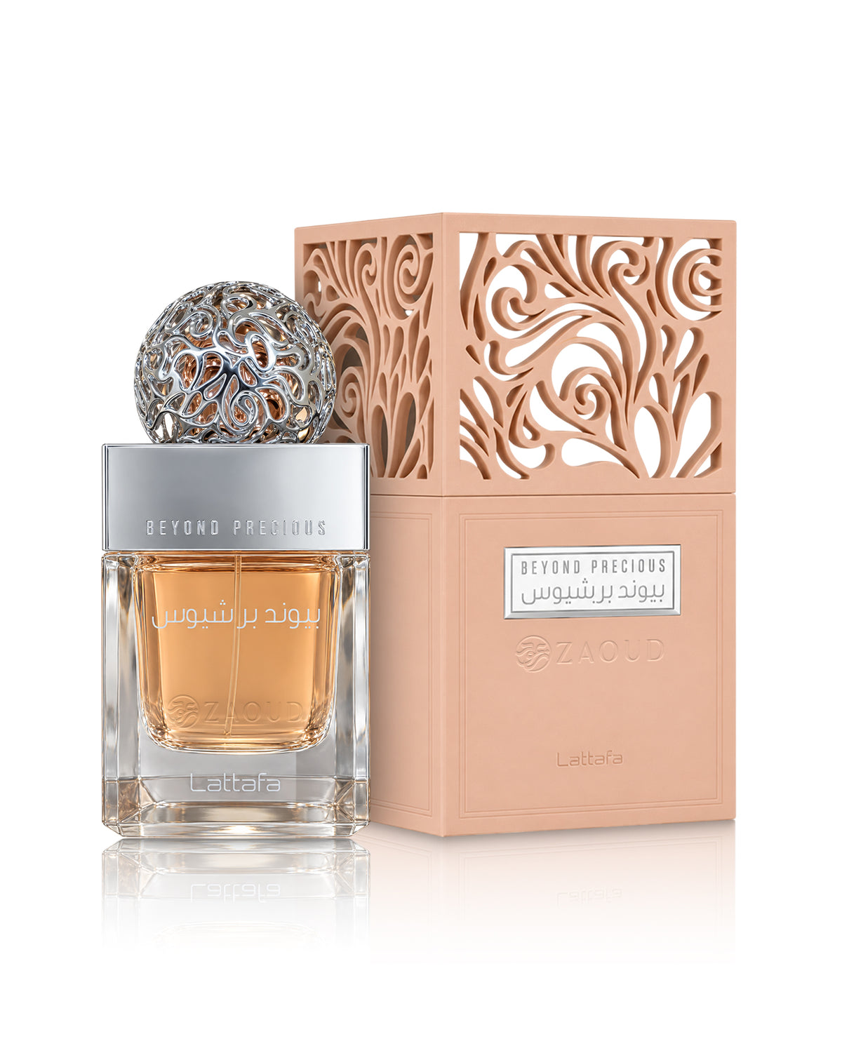 A bottle of lattafa Beyond Precious perfume with a silver cap and ornate silver top, next to its peach-colored box with intricate cutout patterns, on a white background.