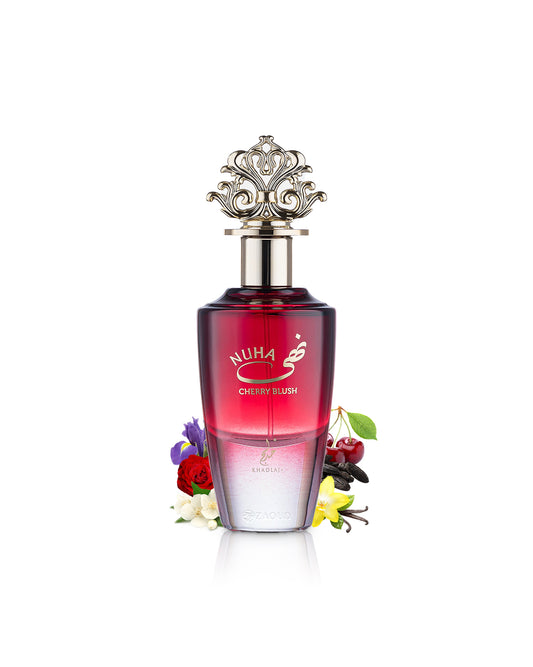 A bottle of Nuha Cherry blush perfume with a metallic silver ornate cap, featuring a red-to-clear gradient bottle, surrounded by cherry blossoms and flowers on a white background.