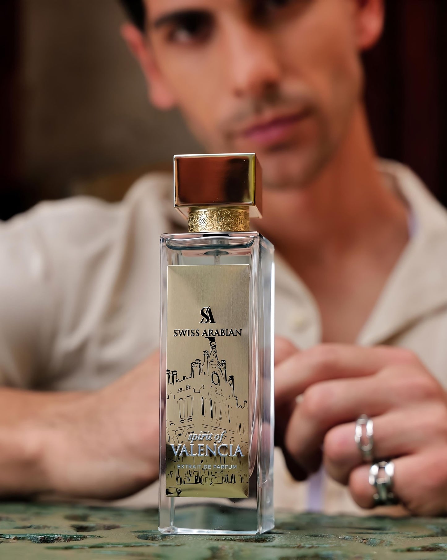 spirit of valencia by swiss arabian perfume bottle photograph with a man model in the background sitting and looking forward.