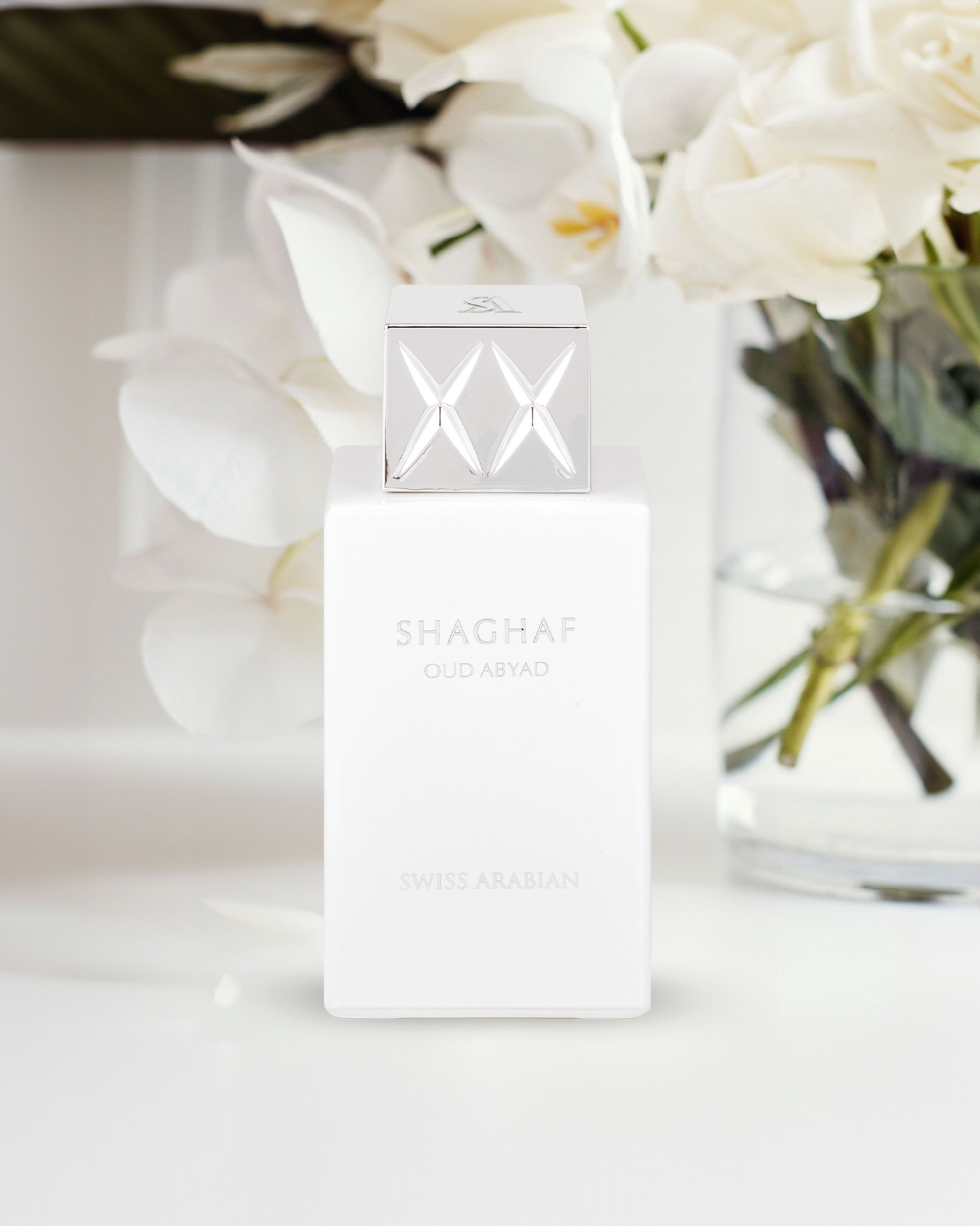 shaghaf oud abyad by swiss arabian perfume bottle phottograph over white surface against some white flowers