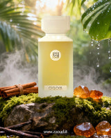A bottle of O’Clock perfume surrounded by amber stones and cinnamon sticks resting on a moss-covered stone, set against a lush natural background with greenery.