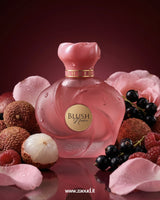 Pink perfume bottle labeled 'Blush' surrounded by lychees, raspberries, and pink flowers on a red background.