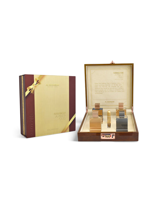 al haramain amber oud collection gift set displayed on a white background, featuring a closed dark brown and gold box next to an open wooden presentation case containing four miniature perfume bottles in gold, rose gold, and silver tones.