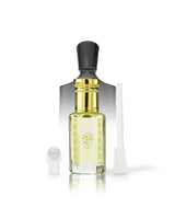 ananas absolu perfume oil bottle with pale yellow liquid, a shiny gold neck, a black cap, and a gold logo on the front. A small white spray atomizer and a white applicator tube are placed beside it on a clean white background.