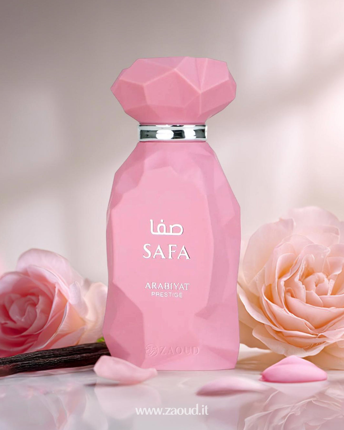 A perfume bottle Safa by Arabiyat Prestige, elegantly designed with a silver collar and white lettering. The bottle is surrounded by soft pink rose petals and a pink rose flower, set against a blurred, soft background.