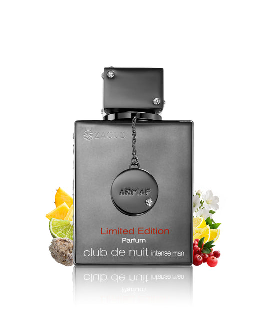 Armaf Club de Nuit Intense Man Limited Edition perfume bottle in a dark metallic gray finish, styled with citrus, berries, and white flowers on a white background with a reflection.