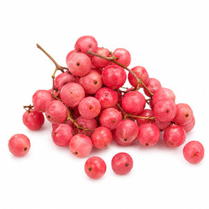 A cluster of small, round, bright pinkish-red berries baie rose, scattered on a plain white background.