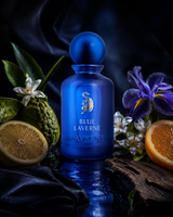 Blue Laverne perfume bottle surrounded by fruits and flowers on a dark background