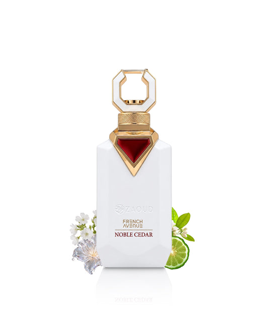 A white rectangular perfume bottle with a gold geometric cap and a red triangular accent on the neck, labeled 'zaoud FRENCH AVENUE NOBLE CEDAR.' The bottle is centered on a white background with small white flowers and a lime slice placed near the base.