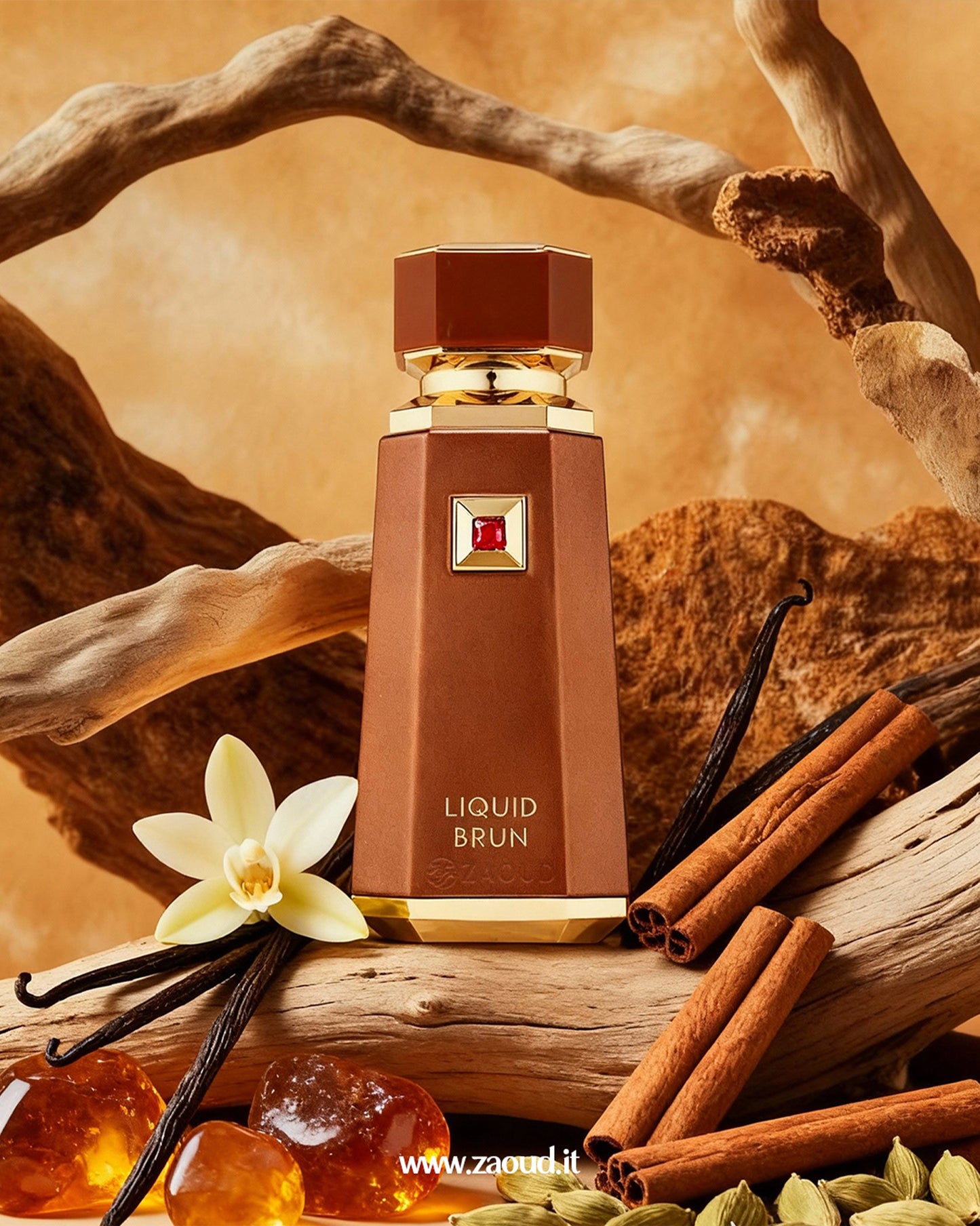 A professional photograph of a perfume bottle labeled ‘LIQUID BRUN’ is displayed. The bottle is elegantly surrounded by, vanilla bean pods, a single vanilla flower, cinnamon sticks, whole green cardamom pods, pieces of amber-colored resin, and various pieces of natural driftwood and rock. The background is a soft, ochre hue, creating a warm and inviting atmosphere.