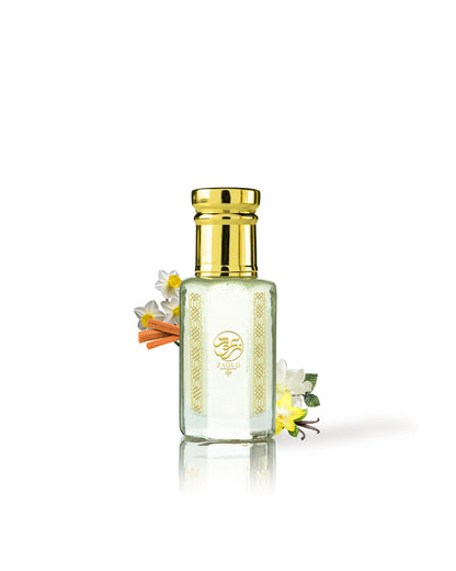 hamam perfume oil bottle with a shiny gold cap and gold decorative patterns on the front, filled with a pale yellow liquid. Small white and yellow flowers with orange accents are tucked behind the bottle on a clean white background.