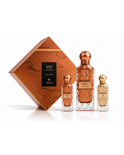 Ibraq elixir de bronze twilight secret set with dor tresor perfume bottles in matching textured glass with metallic rose-gold and gold caps, displayed beside a diamond-shaped rose-gold presentation box on a clean white background.