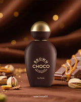 Khadlaj Brown Choco perfume bottle surrounded by chocolate, caramel, and pistachios shows besides with blurry background