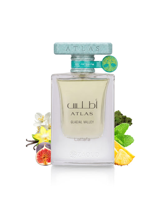 A clear rectangular perfume bottle lattafa ATLAS GLACIAL VALLEY, filled with pale yellow liquid, centered on a white background with decorative flowers, fruit, and mint leaves around it. The bottle has a pale blue cap and a small green-and-yellow tag attached near the neck.