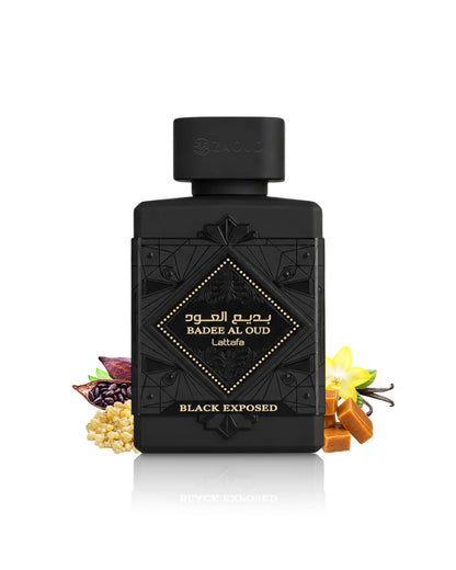 A black rectangular perfume bottle labeled lattafa badee al oud black exposed, with decorative embossed details and gold lettering, centered on a white background. Small fragrance ingredients and a yellow flower are arranged around the base of the bottle.