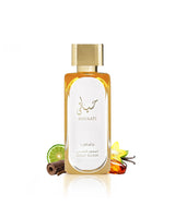 Lattafa Hayaati Gold Elixir with a gold cap and white label, surrounded by decorative ingredients including a lime slice, cinnamon stick, vanilla flower, and amber liquid, on a white background with a soft reflection.
