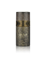 A cylindrical perfume bottle from the brand lattafa, named Fearless, featuring a textured dark gray and gold marble-like design with a gold brick pattern band around the middle and gold Arabic lettering.