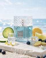Lattafa Khamrah Waha perfume bottle styled with cucumber, lemon, ginger, blueberries, and ice cubes by the sea, highlighting its fresh aquatic citrus vanilla fragrance profile.