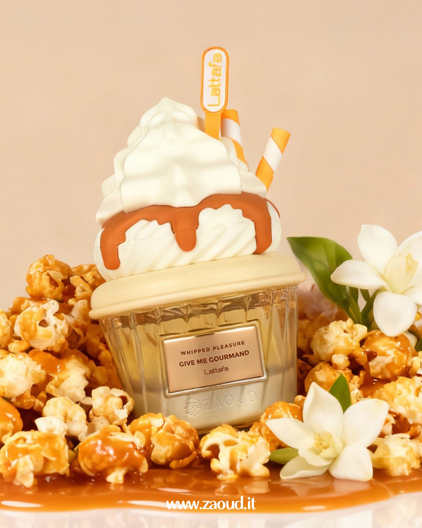 Close-up of the Lattafa Whipped Pleasure Give Me Gourmand fragrance bottle, which is creatively designed to look like a dessert cup topped with a swirl of white whipped cream and caramel sauce. The bottle is sitting in a pile of caramel-coated popcorn and decorated with small white flowers.