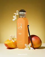 Yara Tous by Lattafa, surrounded by mango slices, white flowers, a vanilla bean, and a whole mango, on a yellow background.