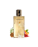 maison alhambra minerale gold perfume bottle shown on a clean white background with small botanical and citrus ingredient props at the base.