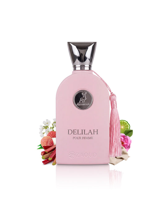 A pink perfume bottle labeled DELILAH POUR femme, featuring a silver cap, a pink tassel, and decorative fruit and flower props on a white background.