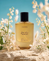 Naseem Musk Safi Elixir perfume bottle surrounded by white flowers with a blue sky background