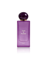 A purple rectangular bottle of Oud & Roses Hair Mist 100ml with a spherical dark purple cap and gold collar, centered on a white background with a soft reflection.