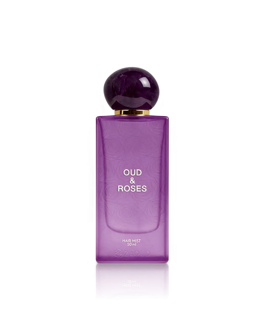 A purple rectangular bottle of Oud & Roses Hair Mist 100ml with a spherical dark purple cap and gold collar, centered on a white background with a soft reflection.