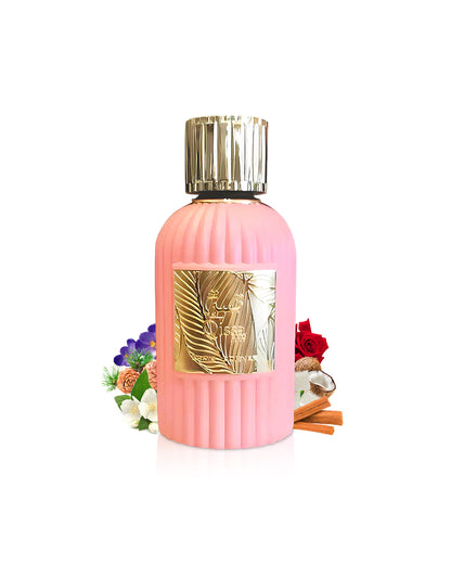 qissa pink by paris corner perfume bottle surrounded with its ingredients like jasmine and coconut with many others like rose shows from behind the bottle against white background