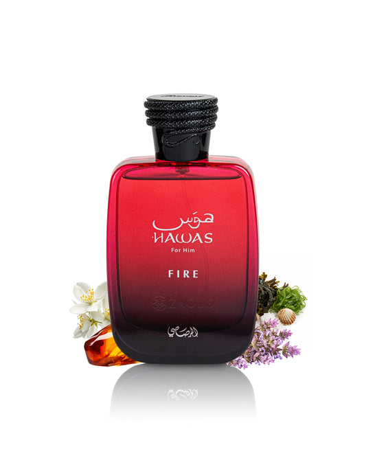 A bottle of hawas Fire cologne for men, featuring a red gradient glass bottle with a black cap, styled with small white and purple flowers on a white background.