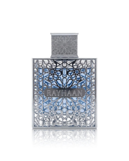 Rayhaan aquatica PERFUME bottle with intricate silver filigree detailing and a blue patterned background, centered on a white reflective surface.