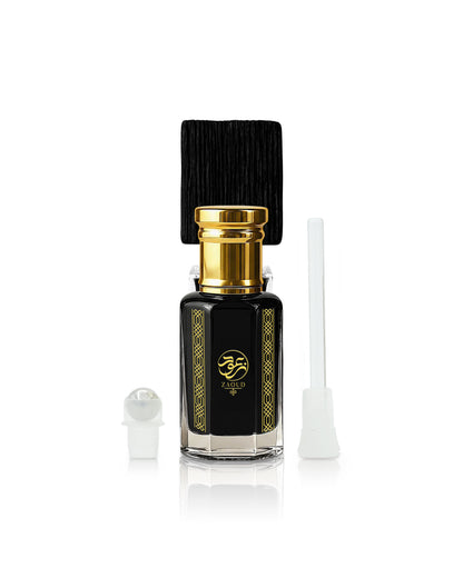 A black glass sabbah perfume oil bottle with a gold cap and gold decorative borders, shown with a black cap, a white dropper, and a white applicator on a white background.