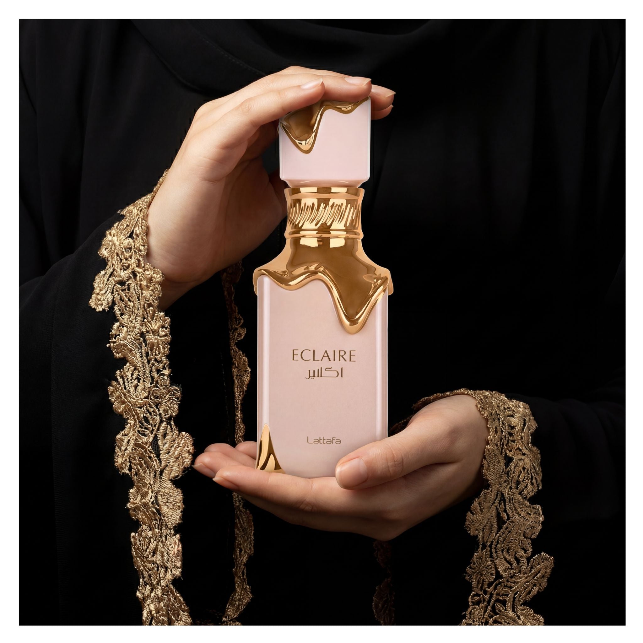 women hands wearing black abaya holding lattafa eclaire perfume bottle 